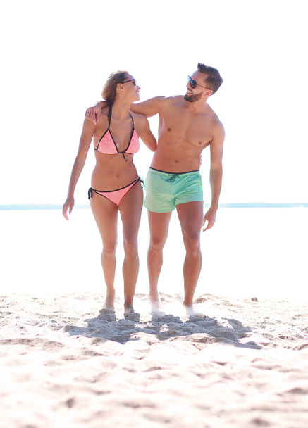 Young couple holding hands and walking on beach. - Foto, imagen