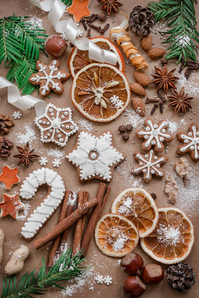 Karácsonyi dekoráció fűszerek és a cookie-kat, az alakja a háttér sötét barna papír hópelyhek. Szemközti nézet. - Fotó, kép