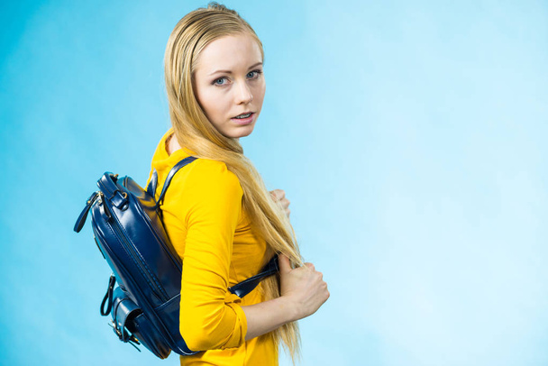 Blonde teenage girl going to school or college wearing stylish backpack. Outfit trendy accessories. On blue - Photo, image