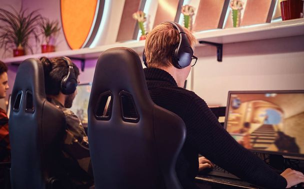 Un equipo de deportistas cibernéticos profesionales, entrenados para el campeonato, juega en un videojuego multijugador en PC en un club de juegos o cibercafé
. - Foto, imagen