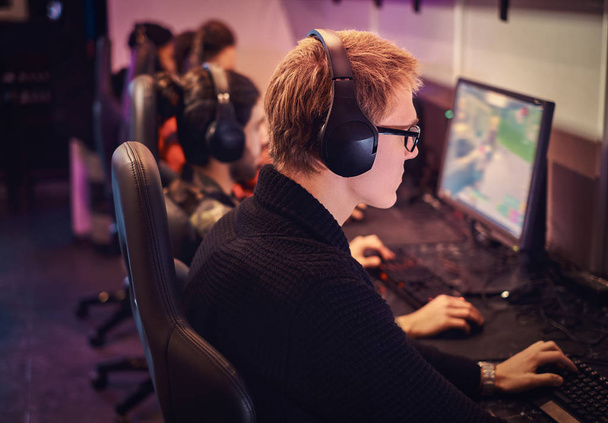 ein Team professioneller Cyber-Sportler, trainiert für die Meisterschaft, spielt in einem Multiplayer-Videospiel am PC in einem Gaming-Club oder Internetcafé. - Foto, Bild