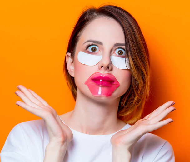 Frau mit Augenklappe für ihre Augen und Pflege Lippen auf orangefarbenem Hintergrund isoliert. Porträt einer natürlichen und wahren Frau, wie sie normalerweise aussieht - Foto, Bild