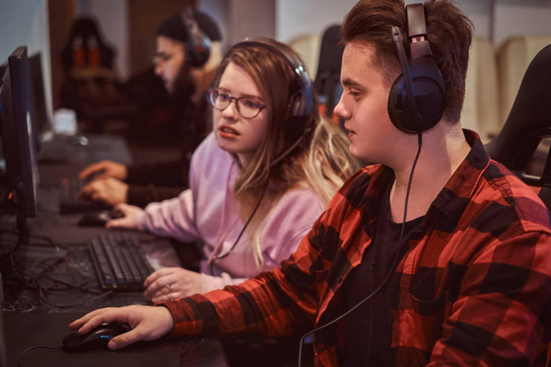 Drużyna nastoletnich graczy gra w multiplayer gra wideo na komputerze w klubie gier. - Zdjęcie, obraz