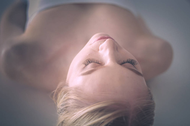 Mujer joven acostada en una mesa de masaje, relajándose con los ojos cerrados. Una mujer. Salón de spa
 - Foto, imagen