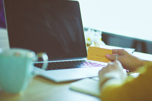 Νεαρή γυναίκα κρατάει πιστωτική κάρτα και χρησιμοποιεί φορητό υπολογιστή. Έννοια online αγορών - Φωτογραφία, εικόνα