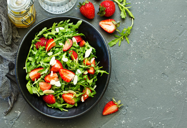 Fresh salad with arugula, strawberries and almonds. Selective focus. - Photo, image