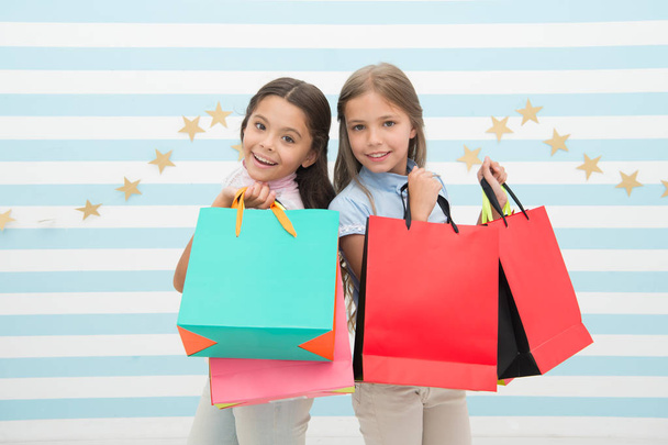 Obsessed with shopping and clothing malls. Discount concept. Kids cute girls hold shopping bags. Shopping discount season. Spending great time together. Children satisfied shopping striped background - Foto, Imagen