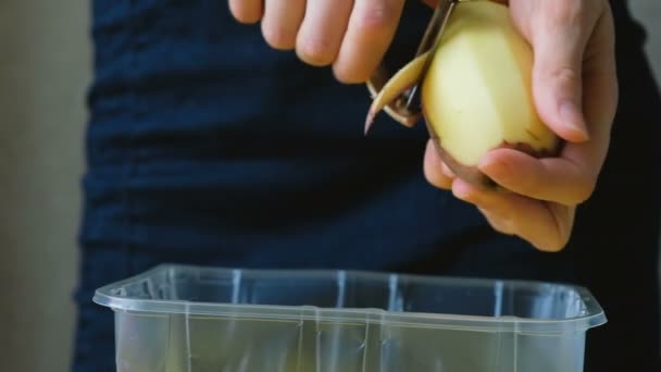 プラスチック容器のクローズ アップの野菜カッターでジャガイモを剥離女性シェフ - 映像、動画