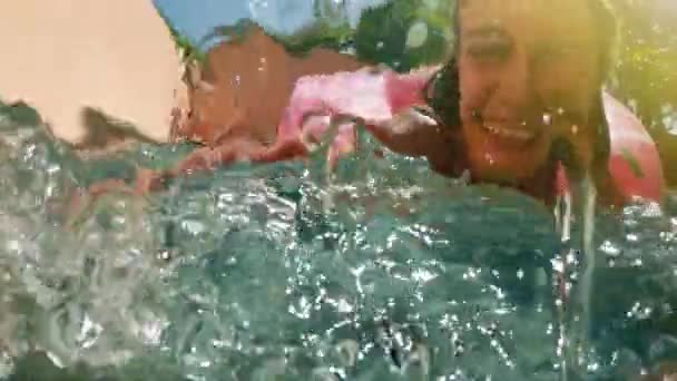 青いビキニで横たわっているプールで膨らませてピンク ドーナツ フロートの日当たりの良い夏の日にサングラスを掛けた女性。カメラを見てください。スイカ ゴムリング リラックスした休暇の女性ビキニ スイミング プール - 映像、動画