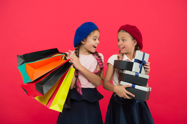 Discount and sale concept. Kids cute girls hold shopping bags. Shopping discount season. Special offer. Great day for shopping. Children enjoy shopping red background. Visiting clothing mall - 写真・画像