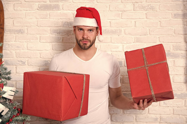 Macho in christmas hat hold wrapped presents - Valokuva, kuva