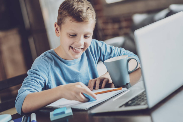 Positive delighted kid using highlighter in task - Photo, image