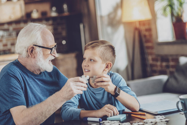 Handsome boy collecting puzzles with granddad - Foto, afbeelding