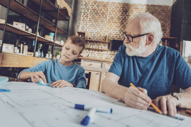 Serious bearded man looking at his grandson - Foto, imagen