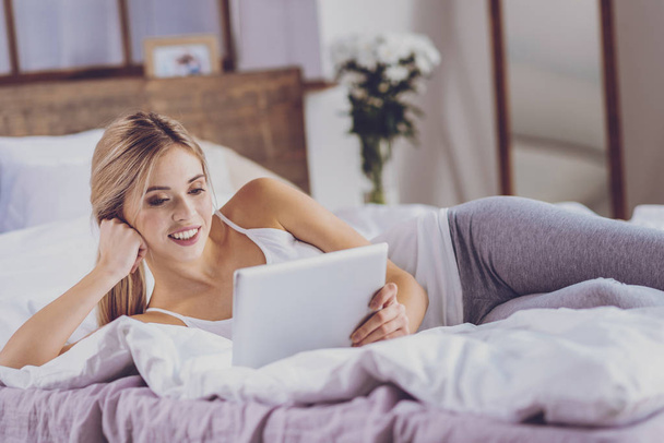 Pretty young woman lying on bed and watching video - Φωτογραφία, εικόνα