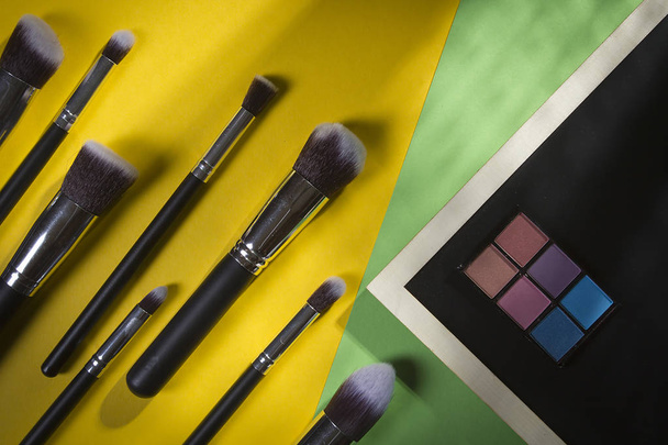 A set of cosmetic brushes on a yellow-green background - 写真・画像