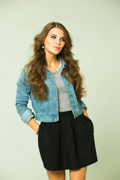 Happy Young brunette woman in a black skirt and blue jeans jacket - Fotó, kép