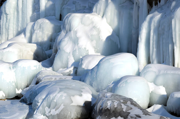 Blocs de glace lisses et murs sur des roches et des pierres gelées, formés pendant le gel du lac Baïkal
 - Photo, image