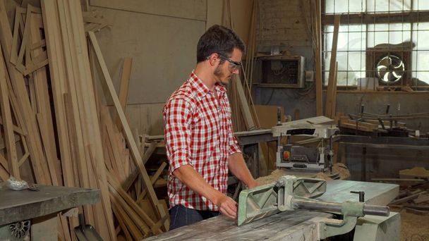 junger Tischlermeister schleift Holzstück in seiner Werkstatt - Foto, Bild
