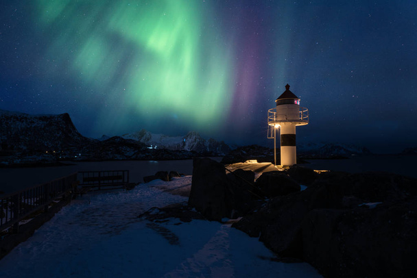 Northern lights, Aurora borealis in Lofoten islands, Norway. Amazing night winter landscape with polar lights and starry sky over the lighthouse in Kabelvag fishing village - Photo, Image