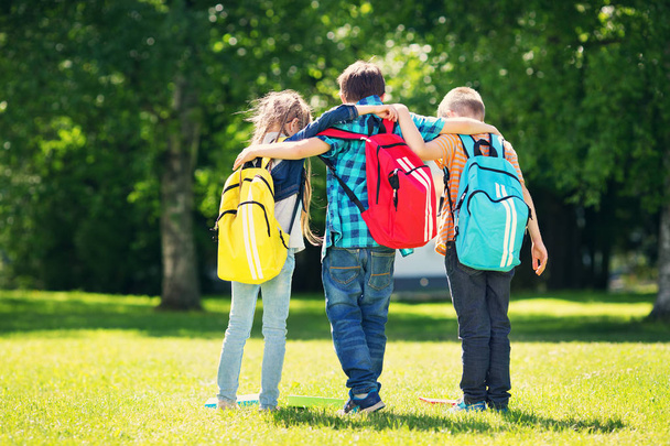 Des enfants avec des sacs à dos debout dans le parc près de l'école. Elèves avec livres et sacs à dos à l'extérieur - Photo, image
