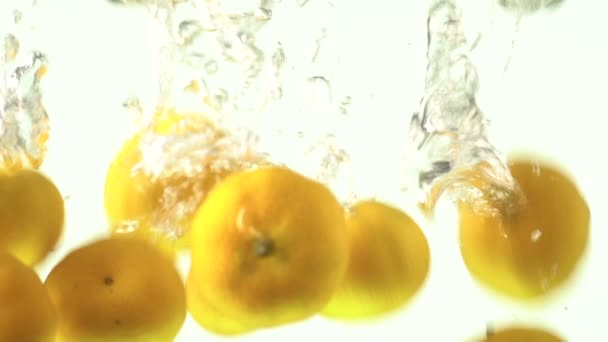Caiu ou caiu pequena gota de frutas laranja na água no fundo branco. Citrinos cair na água imagens de alta resolução Full HD 1920x1080 para alimentos e bebidas categoria
 - Filmagem, Vídeo