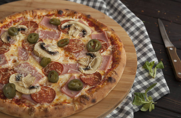Πίτσα, φρέσκια πίτσα με μοτσαρέλα, ντομάτα και τυρί. Ιταλική πιτσαρία. Φρέσκια πίτσα στο τραπέζι της κουζίνας - Φωτογραφία, εικόνα