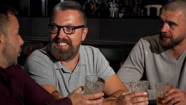 Groupe d'amis masculins matures riant et parlant autour d'un verre de whisky au bar
 - Photo, image