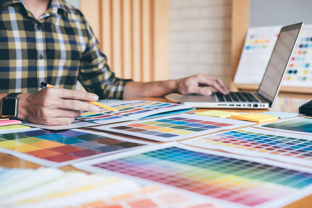 Mladí kreativní grafik pomocí grafického tabletu k výběru barvy vzorníku ukázek chart pro výběr barevné pracovní nástroje a příslušenství na pracovišti. - Fotografie, Obrázek