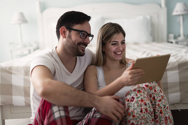 Young attractive couple using digital tablet in bedroom - Foto, imagen