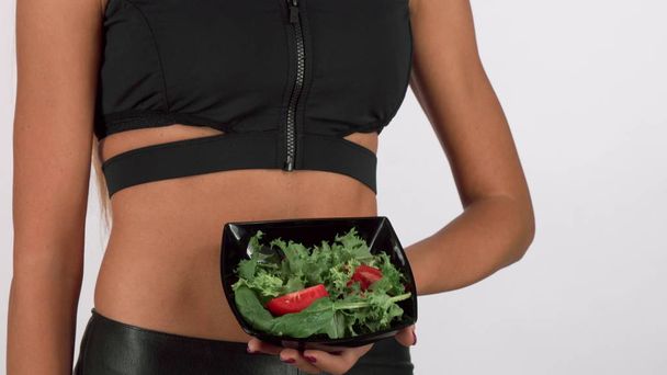 athletische Frau in Sportkleidung mit einer Schüssel frischen Salats - Foto, Bild