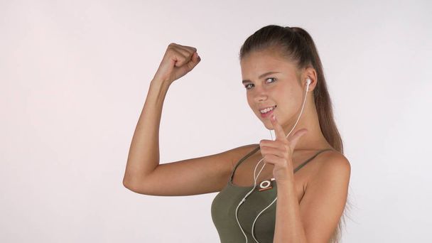 Happy beautiful sportswoman showing her biceps, pointing to the camera at you - Foto, imagen