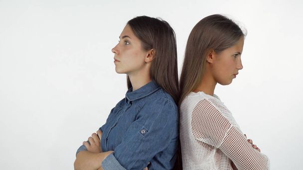 Duas amigas de pé de costas para trás olhando com raiva depois de ter uma briga
 - Foto, Imagem