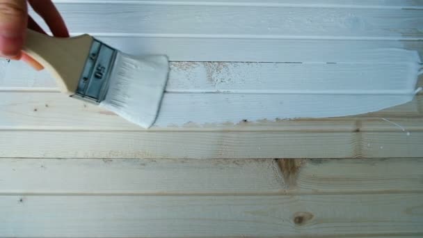 Художник ведет свою кисть вдоль деревянной доски с белой краской в замедленной съемке, вид сверху
 - Кадры, видео
