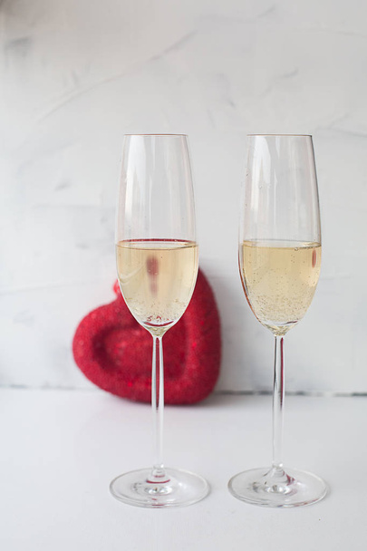two festive glasses of champagne on a white background with a red heart on Valentine's Day - Foto, immagini