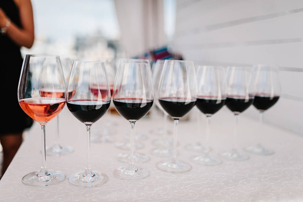Many glass of red wine on a table near bar counter. Glasses with wine. Filled with half and stand on the holiday table. Furshet. selective focus. - Zdjęcie, obraz