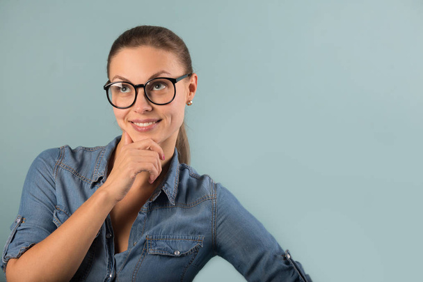 beautiful young girl in a denim shirt with glasses on a blue background - Foto, afbeelding