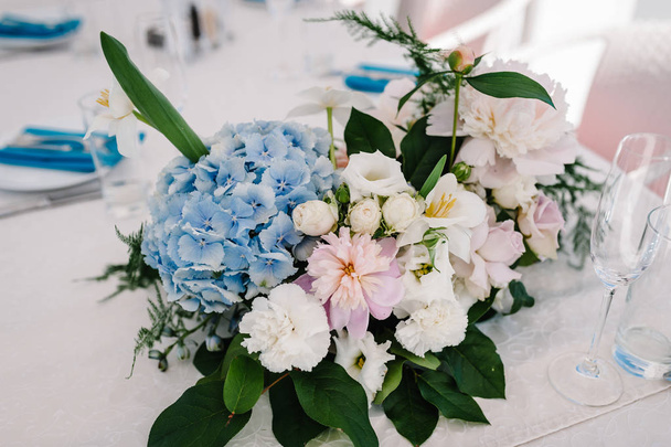 A composition of flowers and greenery is on a festive table at the wedding banquet hall. Close up. - Valokuva, kuva