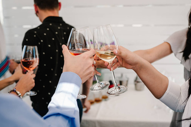 ¡Salud! La gente celebra y las manos se levantan con copas de vino para brindar. Grupo de hombres y mujeres animando con champán espumoso en el restaurante en la fiesta
. - Foto, Imagen