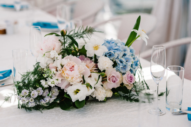 A composition of flowers and greenery is on a festive table at the wedding banquet hall. Close up. - Photo, Image