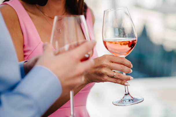 Μια φωτογραφία κόμμα της γυναίκας και του άνδρα να κρατάει ένα ποτήρι κρασί στο κόμμα. Κορίτσι, κυρία στέκεται στο παρασκήνιο και ποτό κρασί. Η έννοια των σχέσεων μεταξύ των ανθρώπων. - Φωτογραφία, εικόνα
