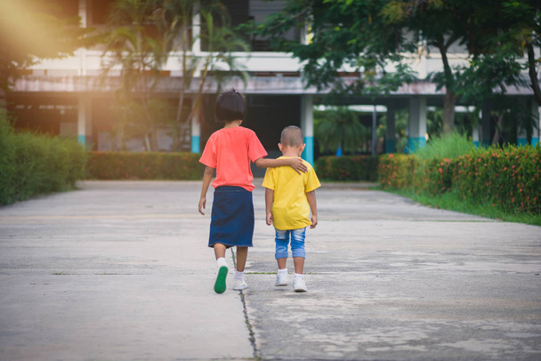 Életlenítés háttér hátsó nézet kis-ázsiai testvérei séta kéz a kézben. szerelem családi fogalmak - Fotó, kép