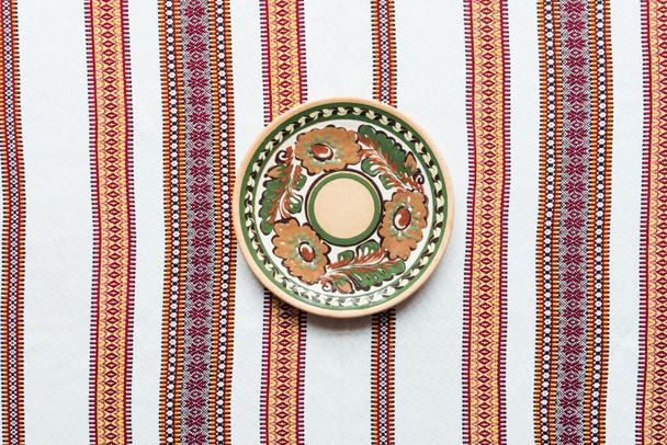 Ansicht des Tellers mit traditionellem Ornament und besticktem Handtuch auf Hintergrund - Foto, Bild