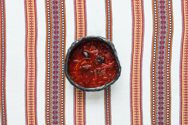 top view of traditional tasty beetroot soup with embroidered towel on background - Photo, Image