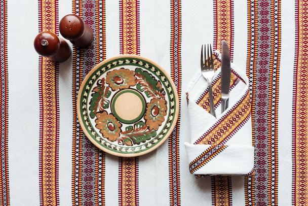 верхний вид традиционной сервировки стола с декоративной тарелкой на вышитую скатерть
 - Фото, изображение