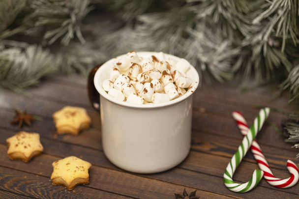 Winter hot Christmas chocolate or cocoa with marshmallow with decorations. A cup of hot chocolate with marshmallows and gingerbread on a Christmas table. - Foto, Imagen