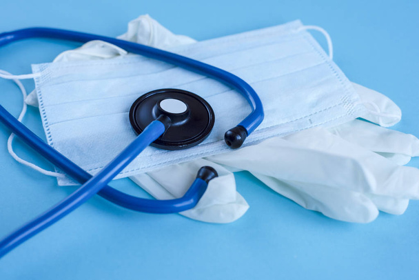 Lääketieteelliset käsineet, naamio ja sininen stetoskooppi sinisellä
 - Valokuva, kuva