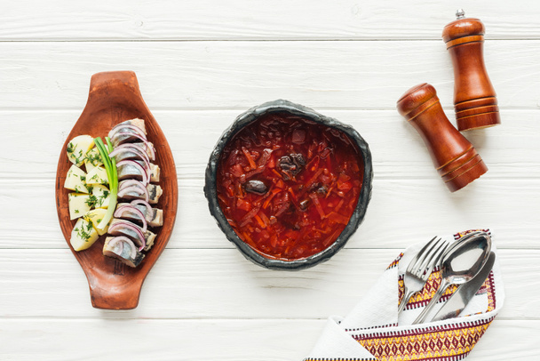 top view of traditional beetroot soup with herring and cutlery on white wooden background - Photo, Image