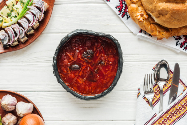 pohled shora tradiční červená řepa polévka s příbory a nádobí kolem na bílém pozadí dřevěná - Fotografie, Obrázek