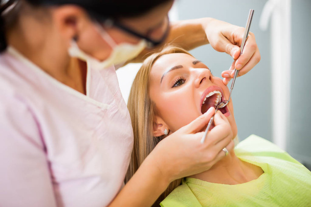 Mladá žena u zubaře. Zubař jí prohlíží zuby..  - Fotografie, Obrázek
